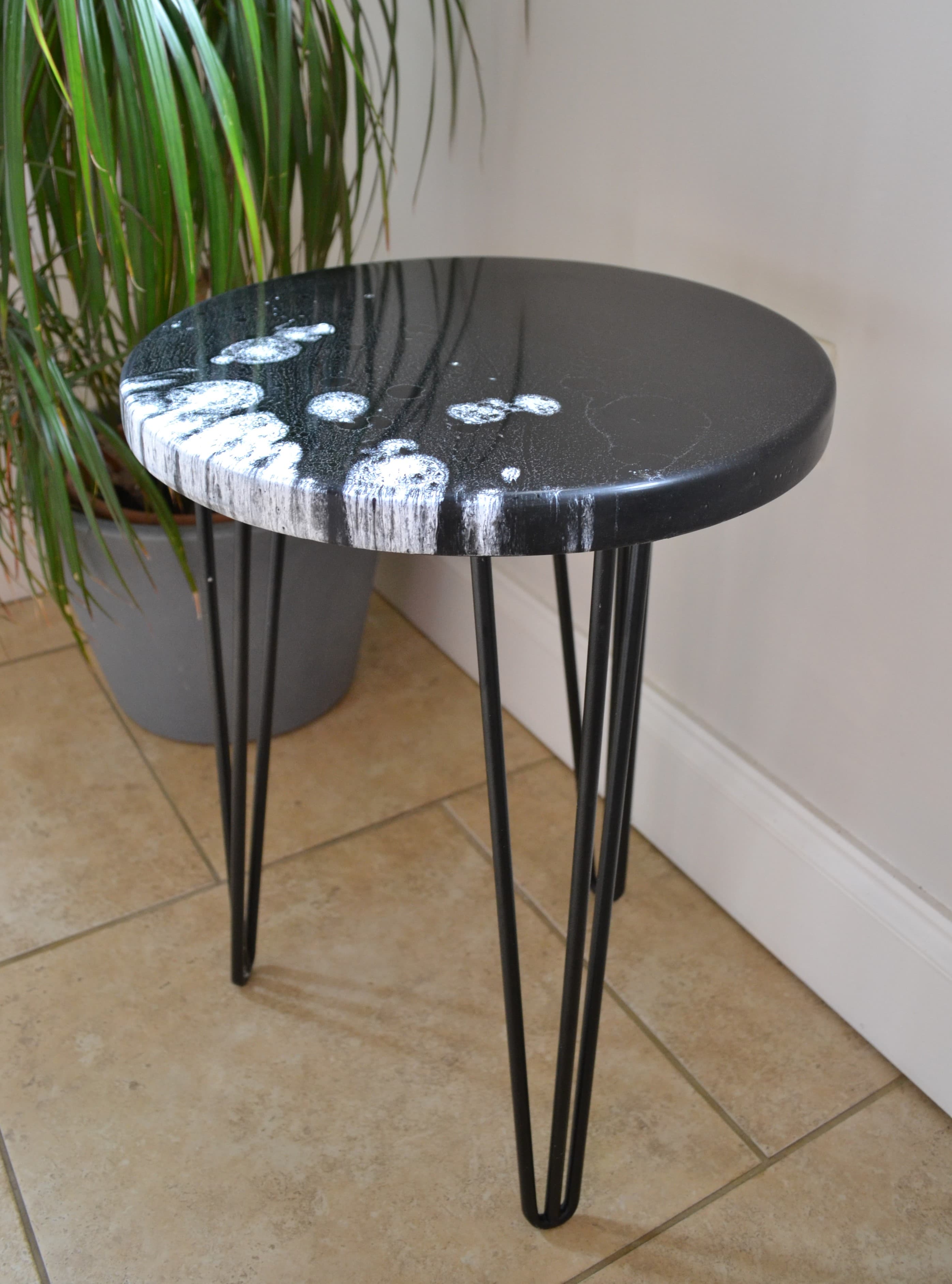 Black round side table made from reclaimed surfboard fibreglass and resin in a bright interior.