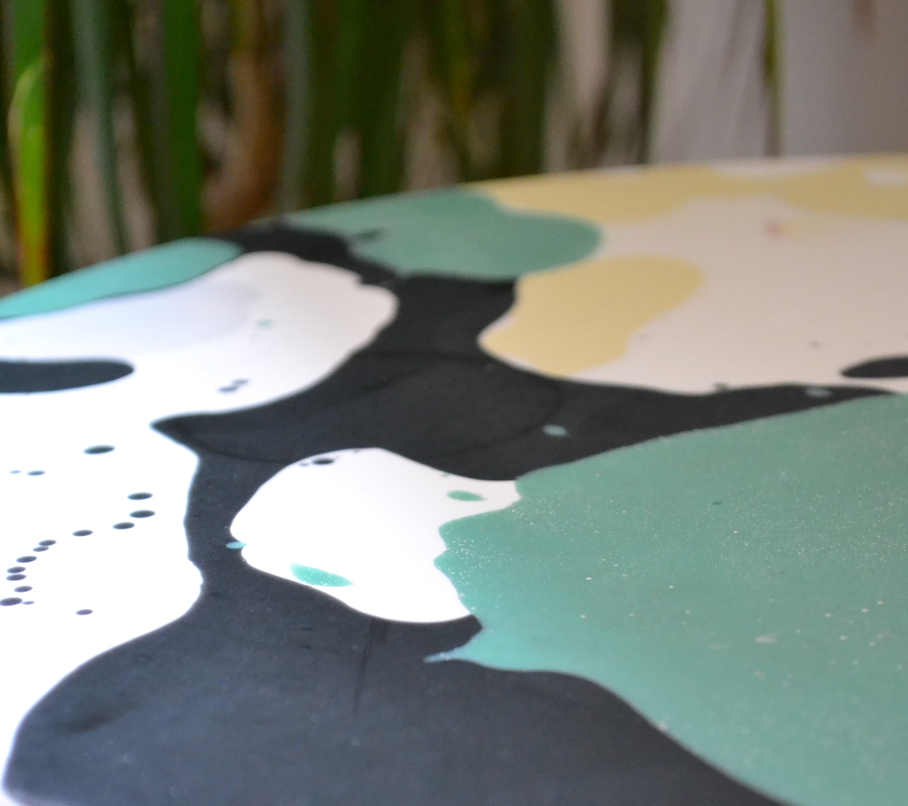 Close crop of green, white and black resin movement on a round tabletop.