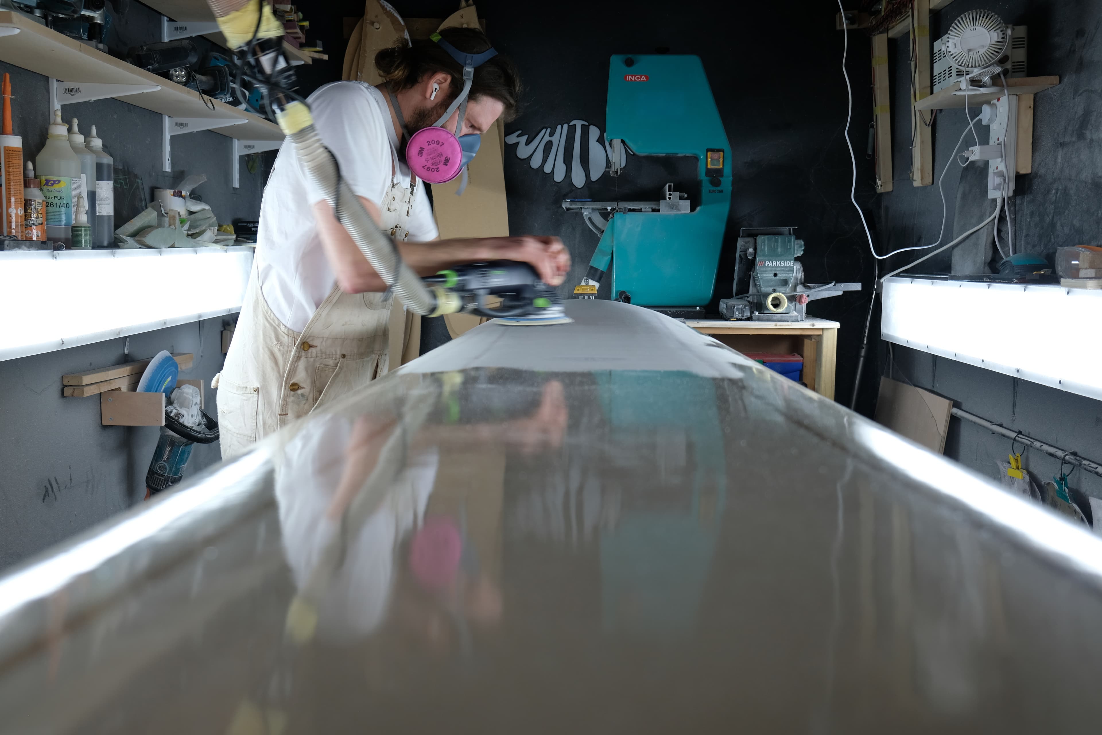 A surfboard blank viewed down the centre line while James works in the shaping bay.