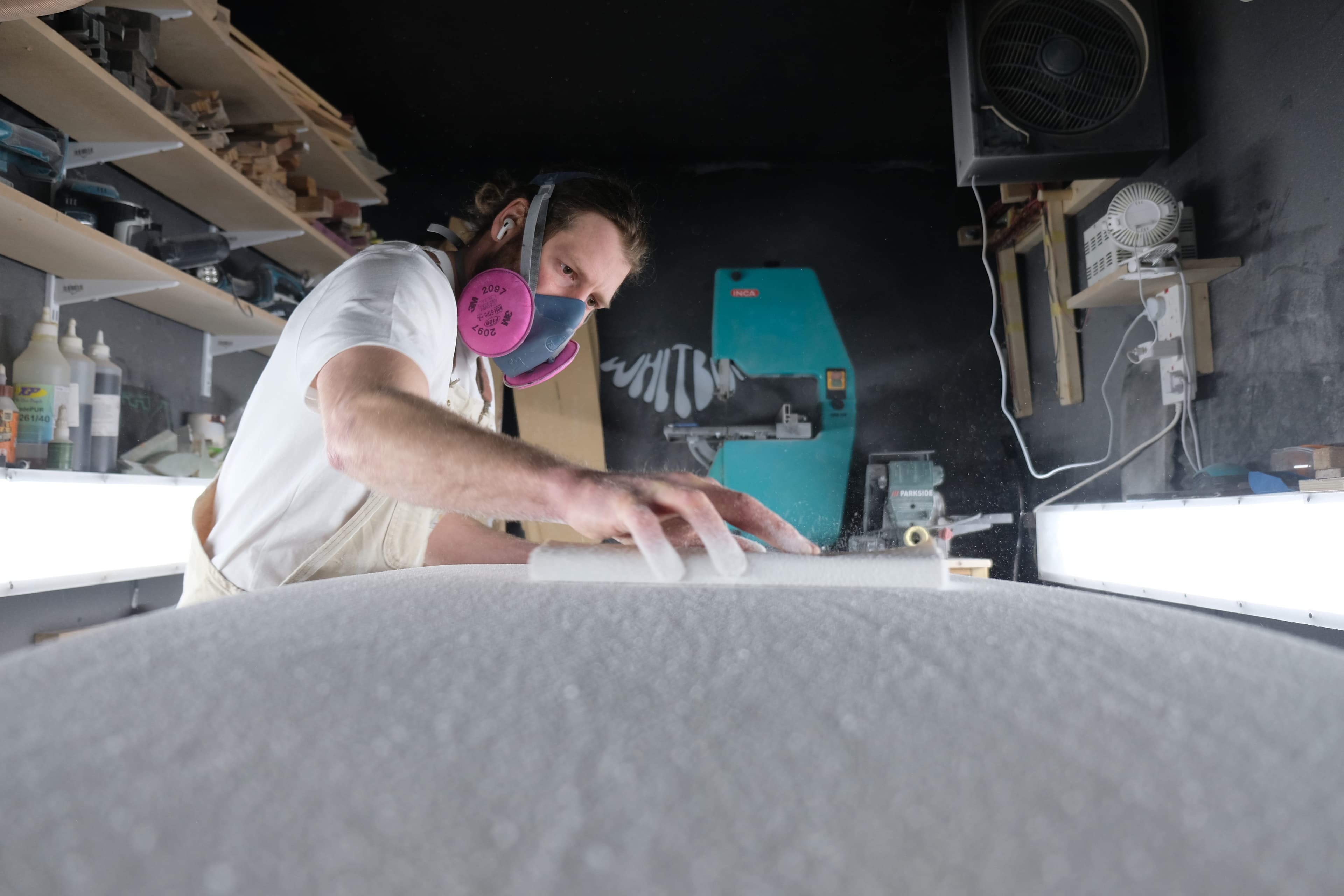 James working on a surfboard blank in the Whitburn Studio workshop.