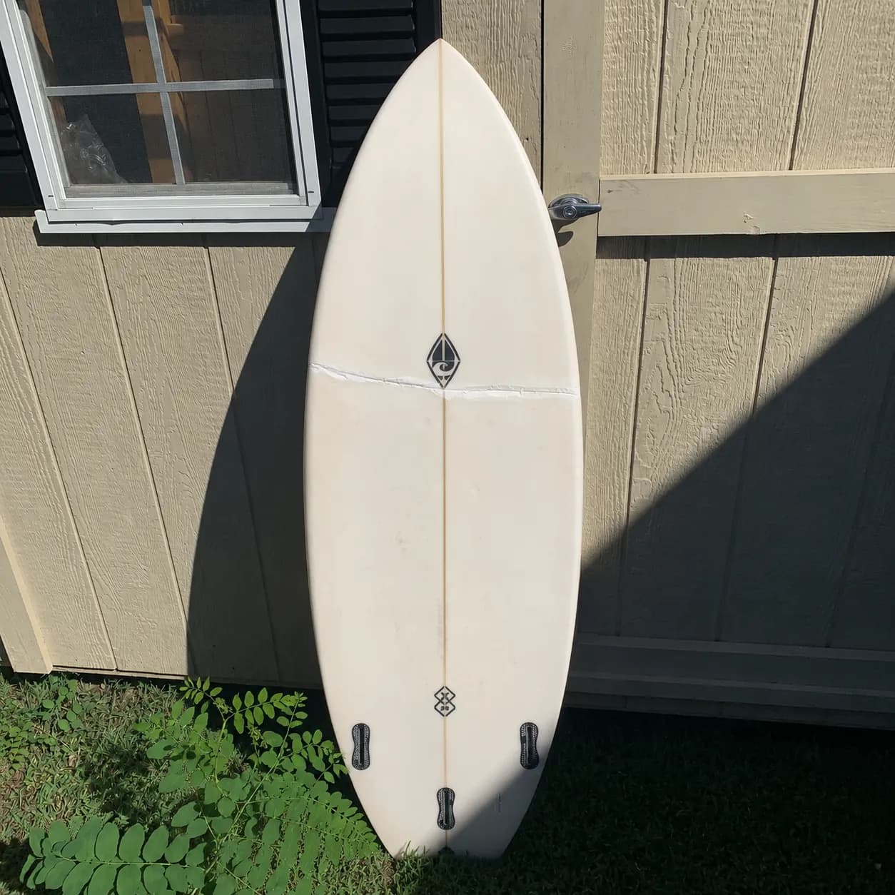 A buckled surfboard showing a structural crease across the board before repair.
