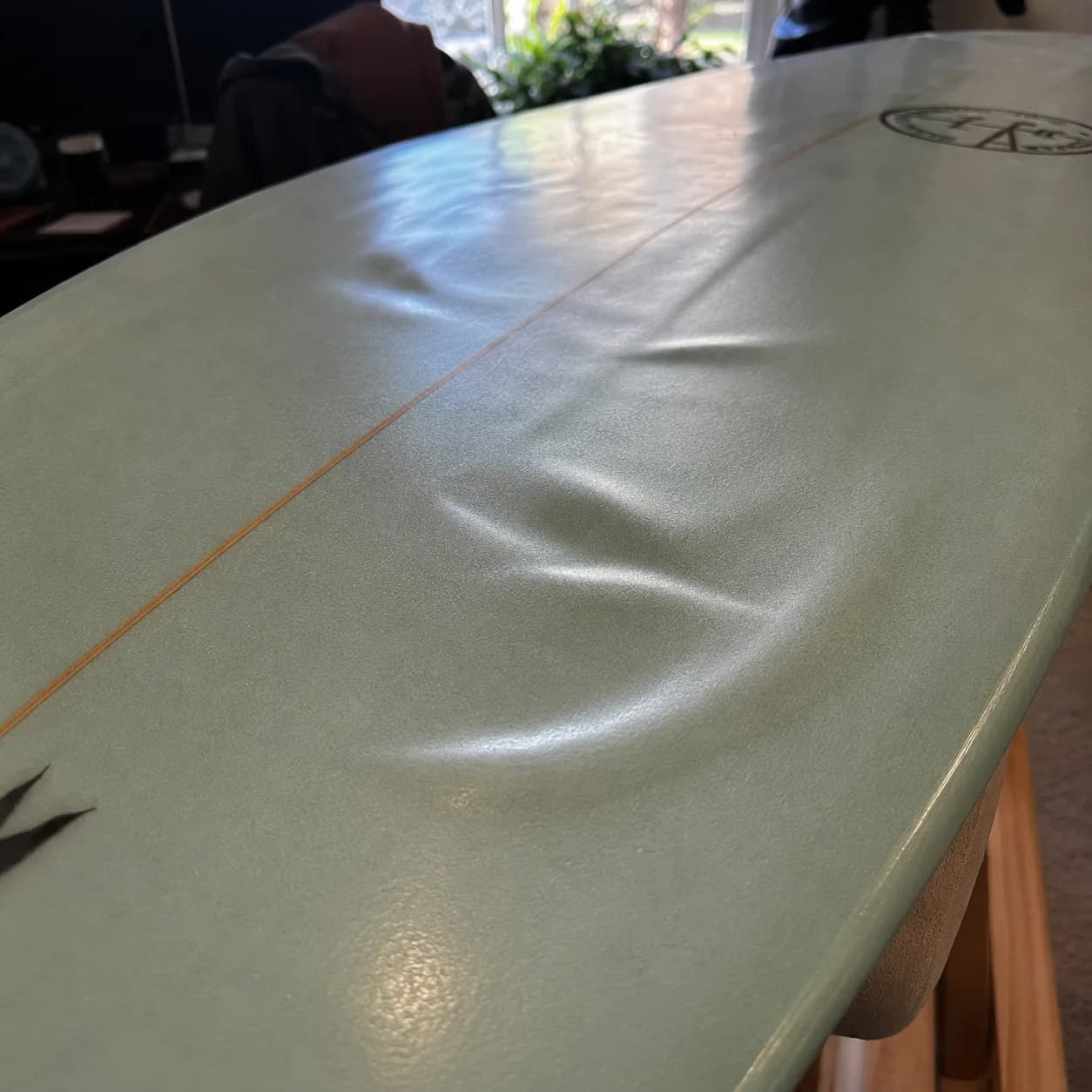A surfboard deck with a raised area of delamination where the laminate has separated from the core.