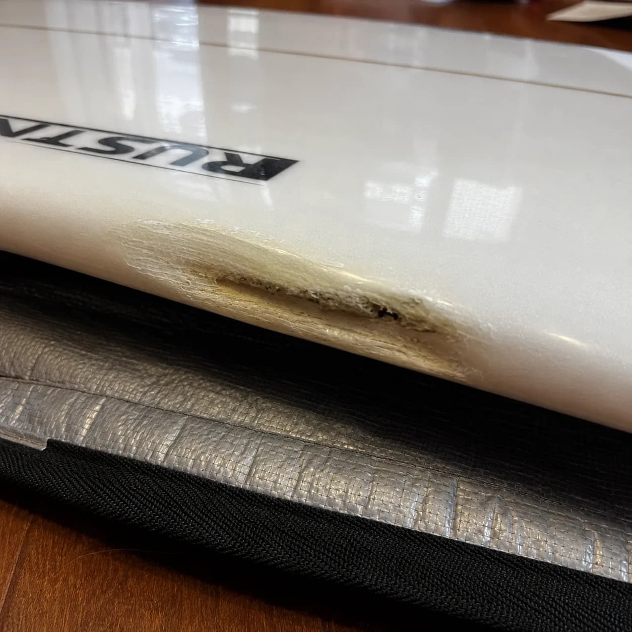 A surfboard with substantial rail damage being assessed before repair.