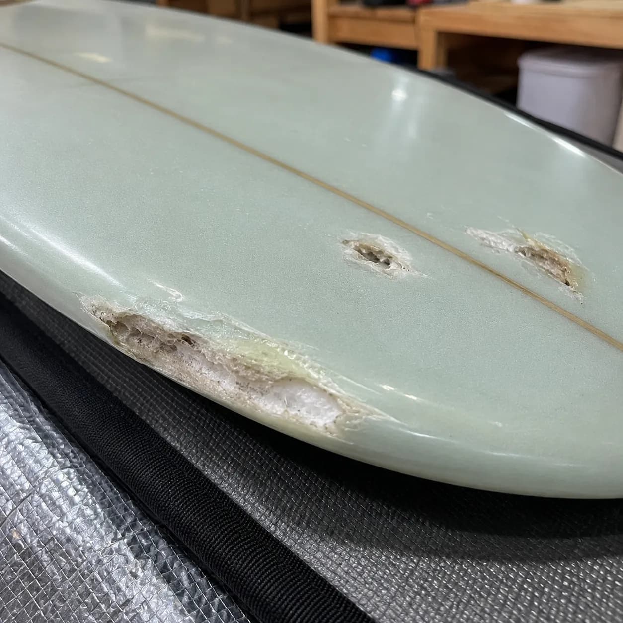 A surfboard with several damaged areas requiring assessment and repair.