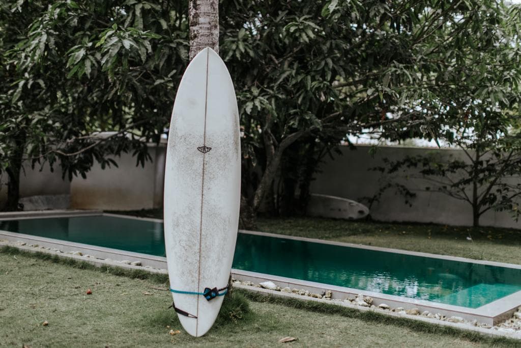 A Whitburn surfboard standing by a swimming pool with the board logo visible.