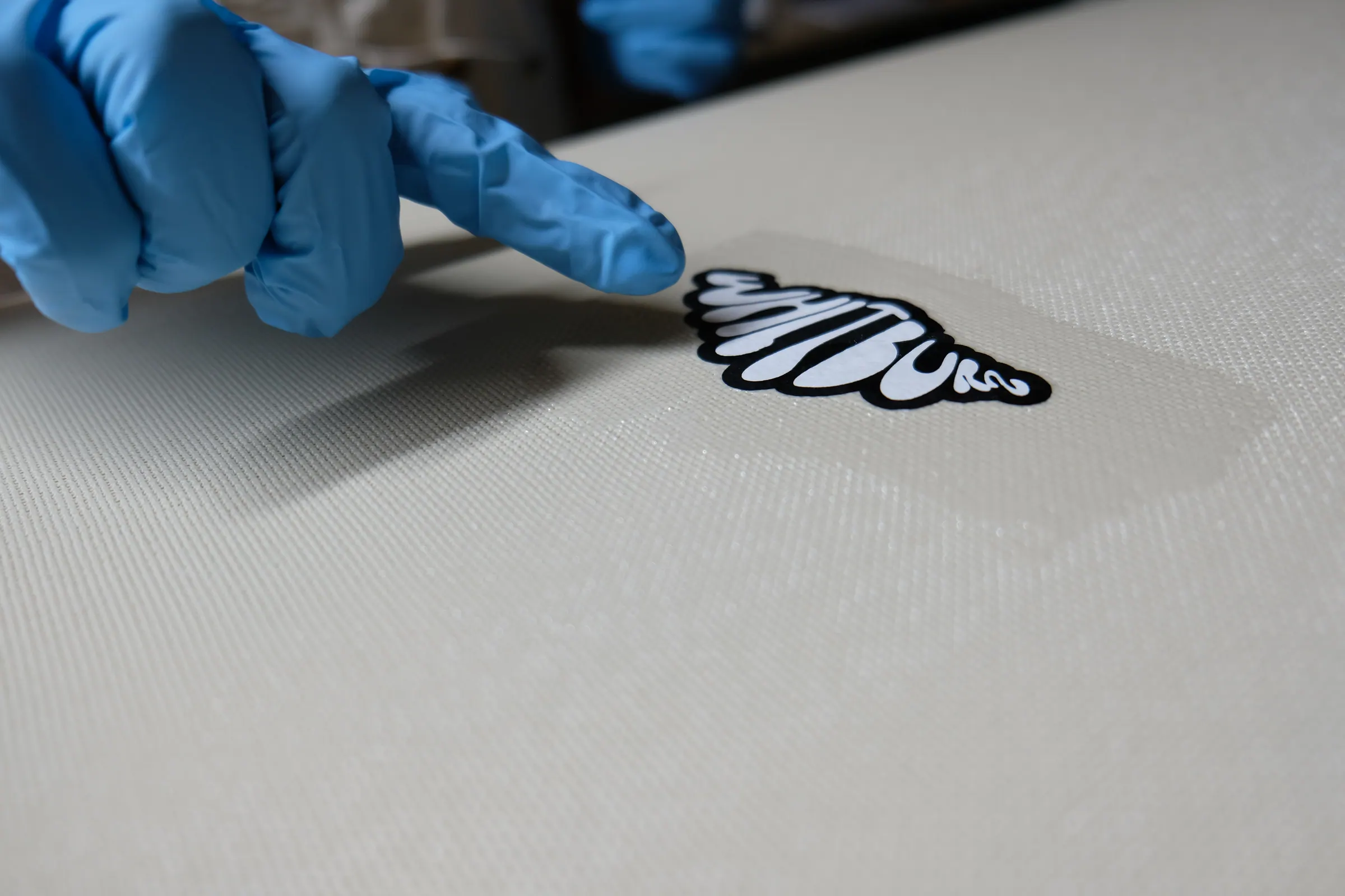 A gloved hand pointing to the Whitburn mark set into fibreglass.